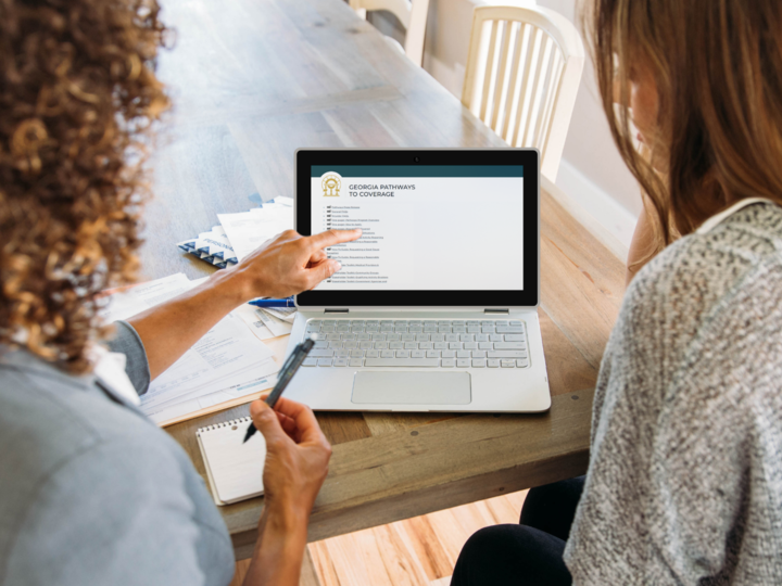 Two women looking at a laptop screen on a table.