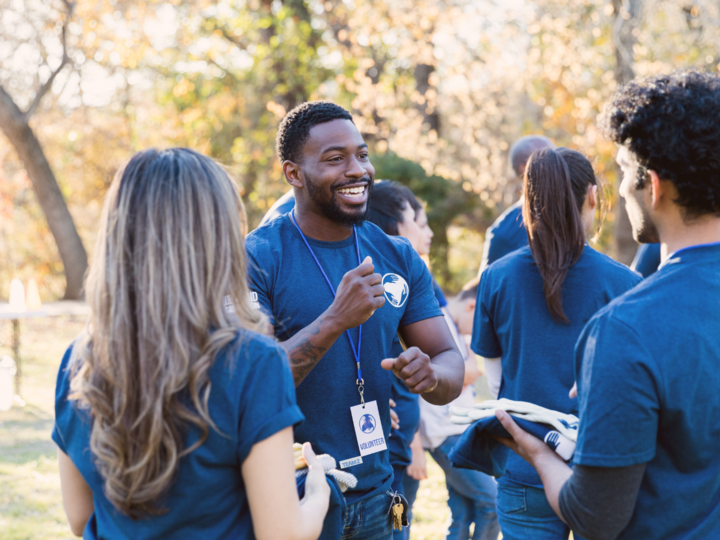 A group of young adults in blue t-shirts gathered outdoors.