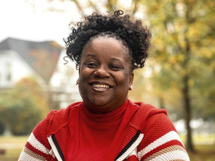 Woman smiling with faded trees and home behind her