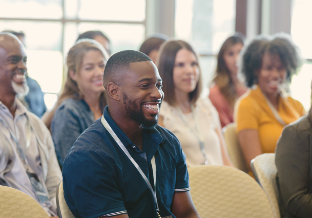 A diverse group of adults is seated at a conference.